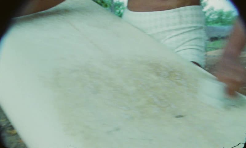 A young woman is cleaning up her surf board