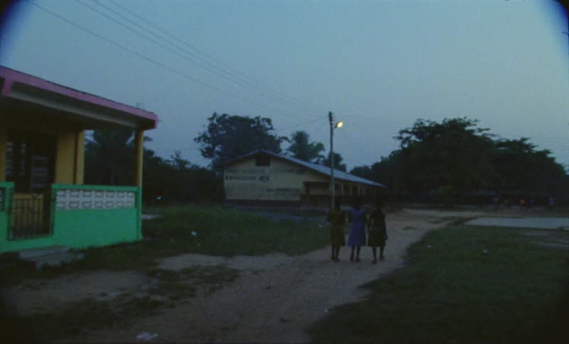 Three girls with short hair and dresses walk on dirt road in the countryside
