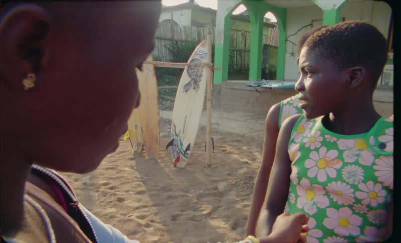 A group of teenage girls putting on wristbands for an event at the beach with surfboards in the background