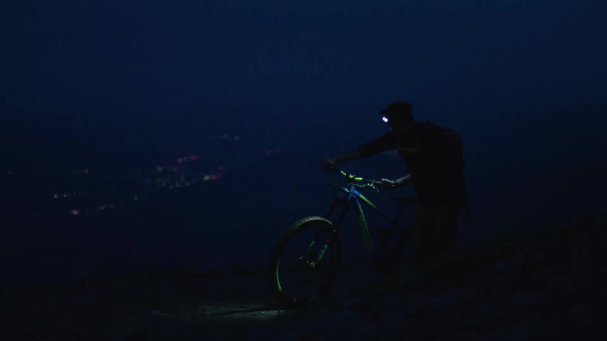 A person is walking with their bike during the night time