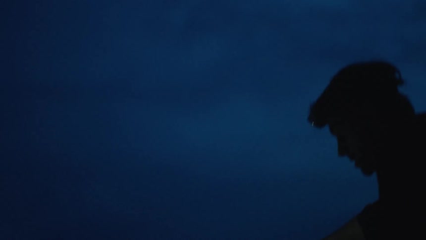 The silhouette of a man wearing a headlamp at night with a backpack on his back