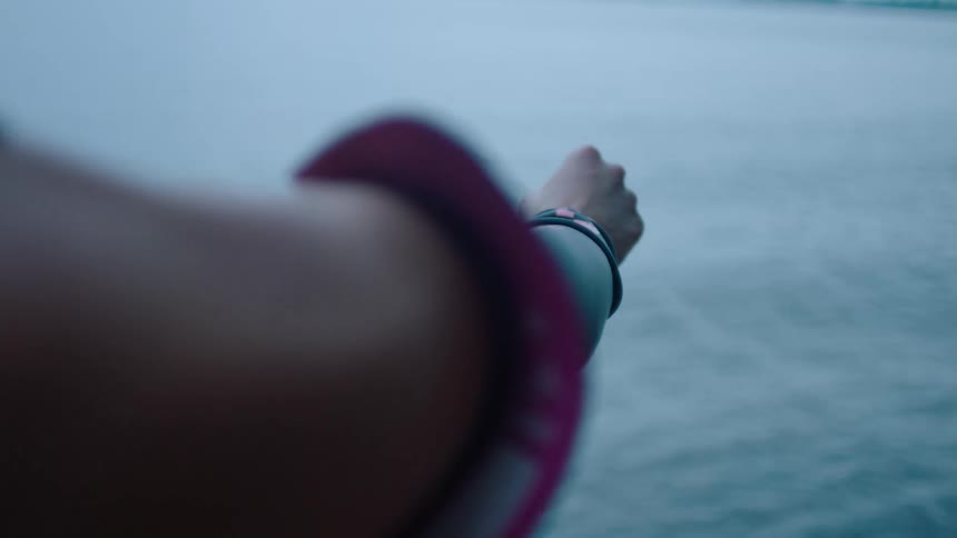 Close up of the arm of a woman while she wears a wet suit on the beach