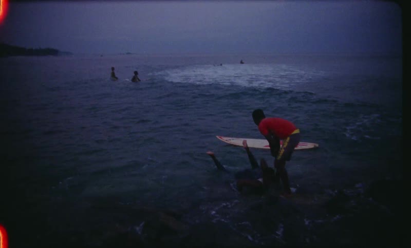 A group of kids swimming in the surf with waves and surfboards at the beach during the day