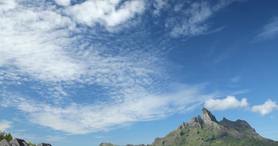 Small huts are on the water with a mountain nearby