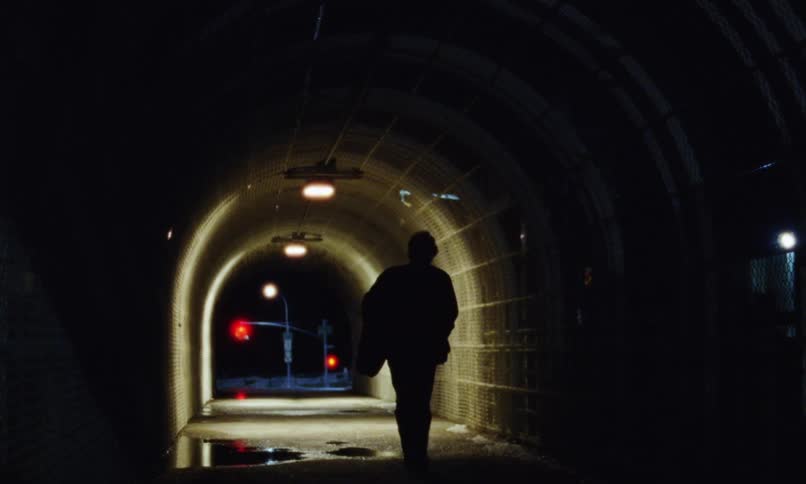 The view is of a man that is walking outdoors at night