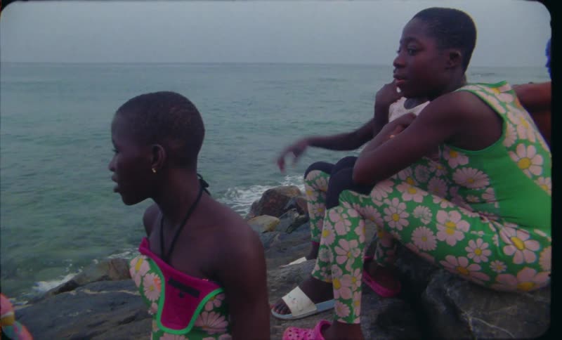 A group of children teenagers and young people sitting on rocks overlooking the ocean