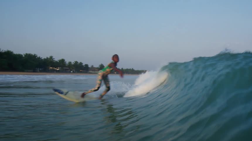 A female is surfing on ocean waves at dusk