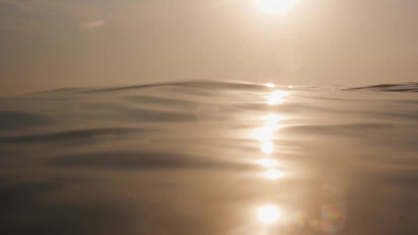 A person is swimming in the ocean water at dusk
