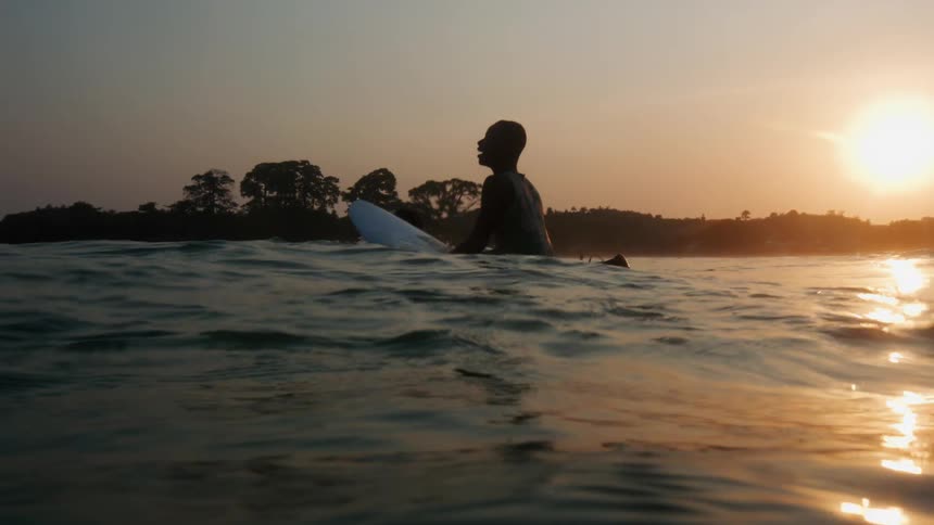 A man sitting on a surfboard in the ocean near the shore