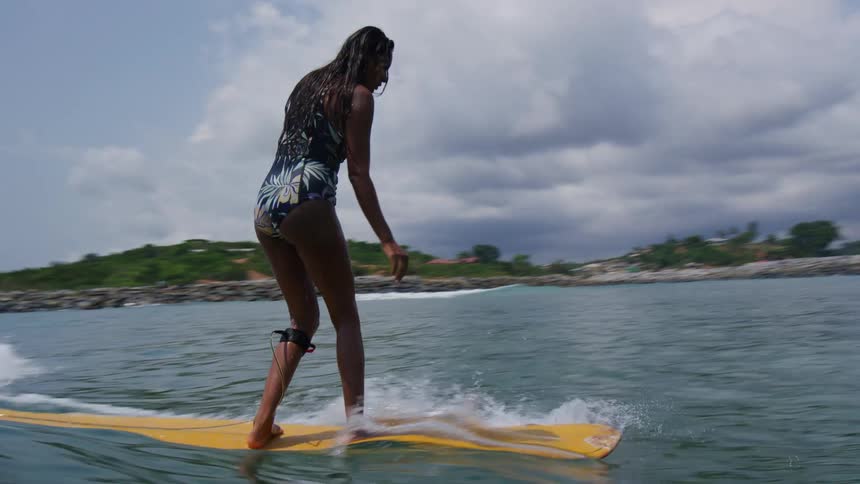 A woman is surfing on the ocean water during midday