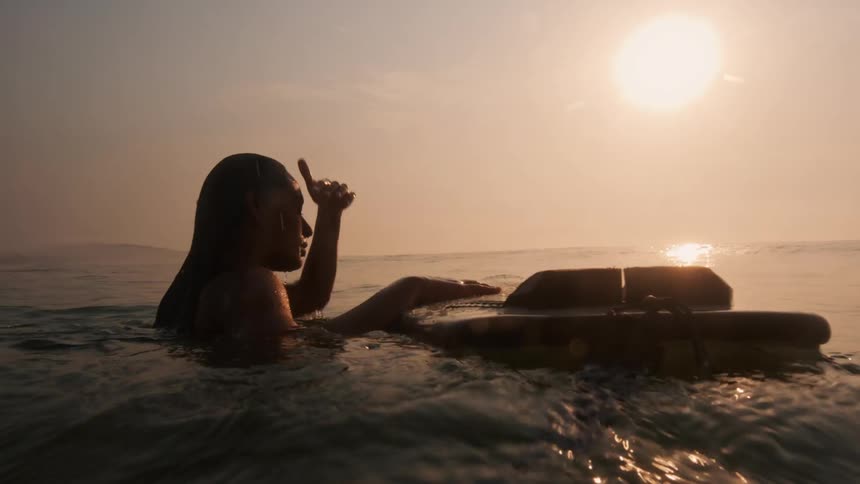 A woman is surfing in the ocean during dusk