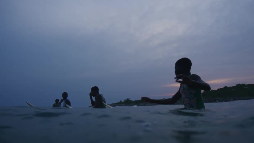 A group of children are surfing in the ocean sea