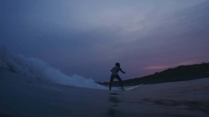 A person is surfing at night in ocean water