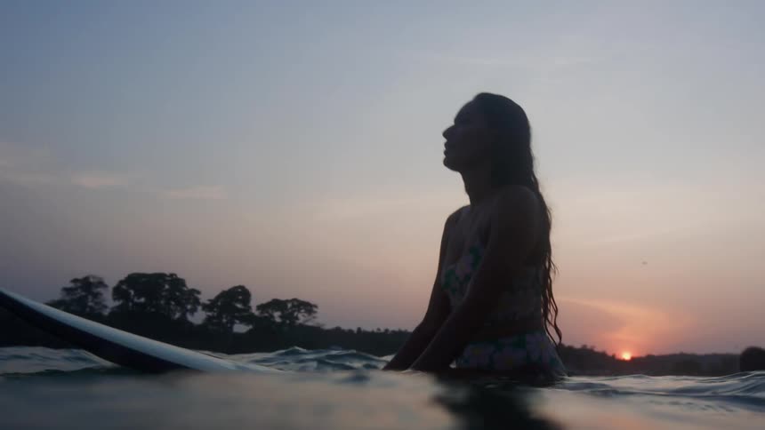 A young woman is on a surf board in the water
