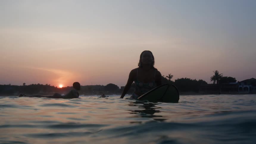 The view is of a young woman that is sitting on her surfboard