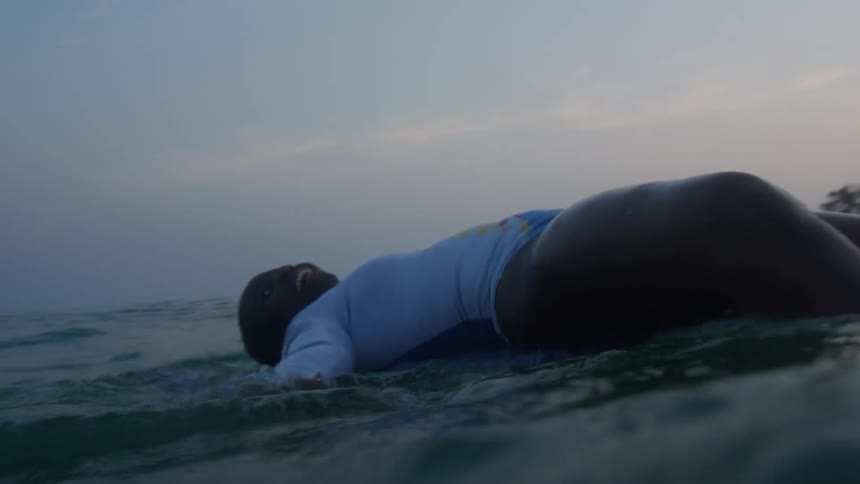 A woman is swimming in the ocean water at dusk