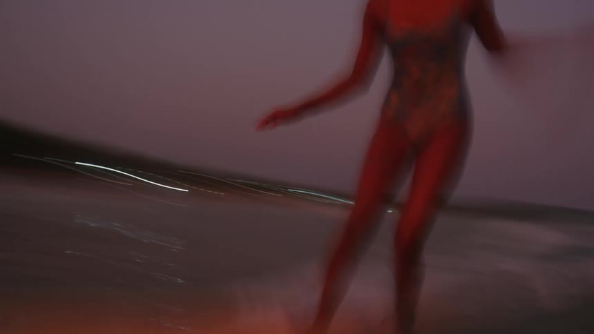 Woman surfs under a red sky