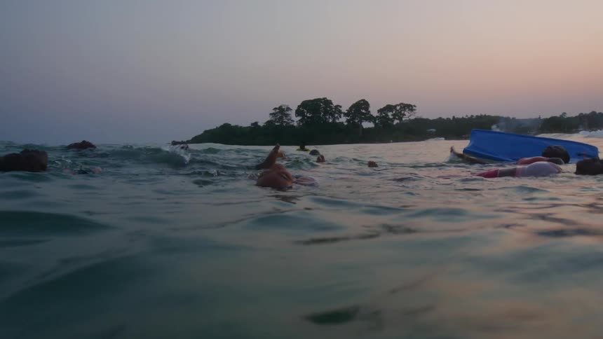 Group of friends relax floating on the calm surface of the ocean near the coast at evening