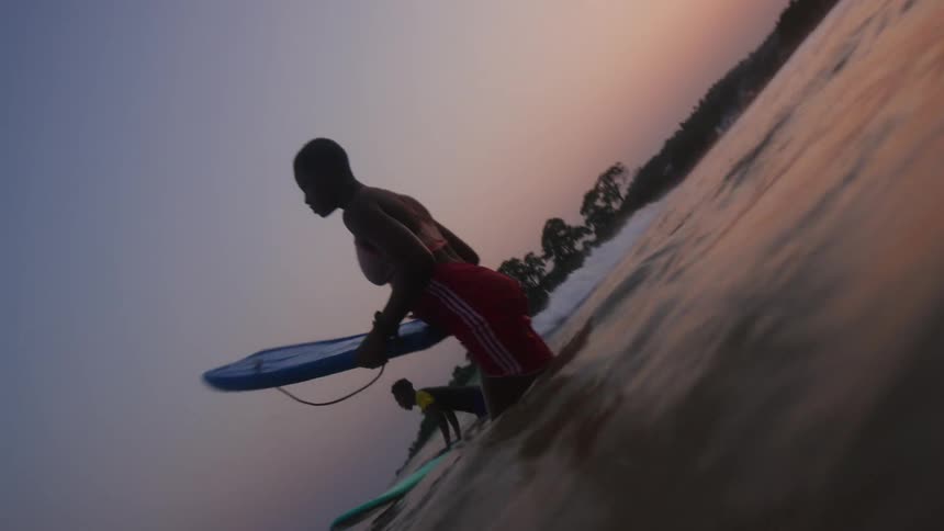 Two people move away from shore using kick boards under a red sky