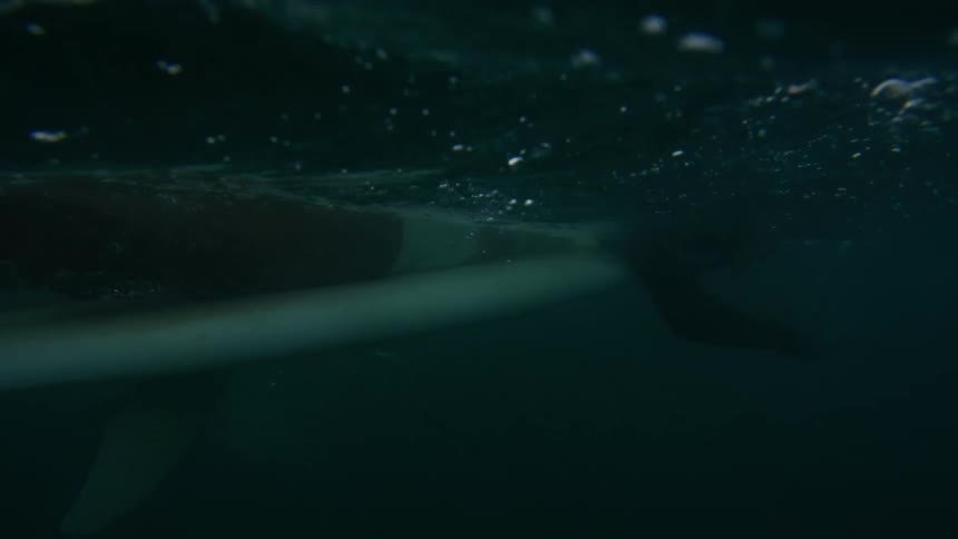 A female is surfing in ocean water at dusk
