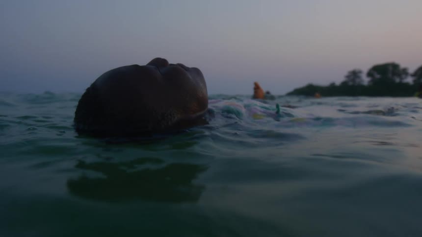A close up of a persons head as they float on their back in the water