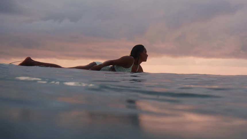 A young woman is surfing outdoors in the middle of the day time