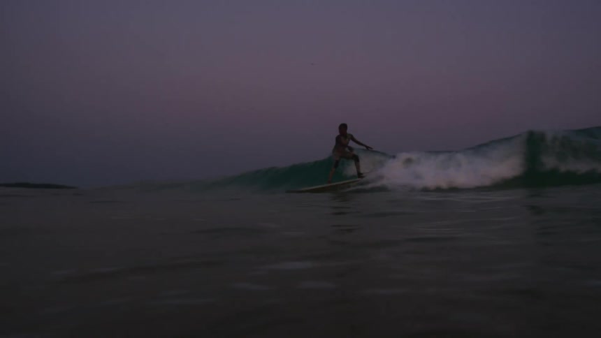 A younger person riding a surf board on a wave in the ocean