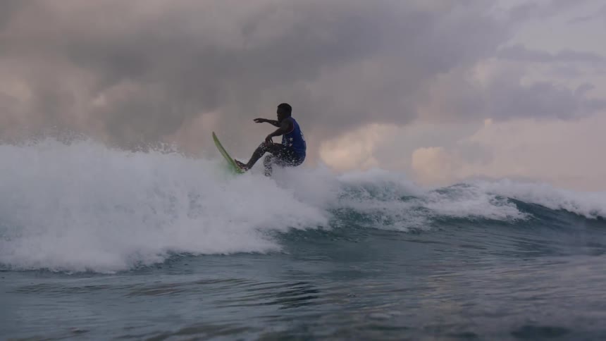 A male is surfing on ocean waves at dusk