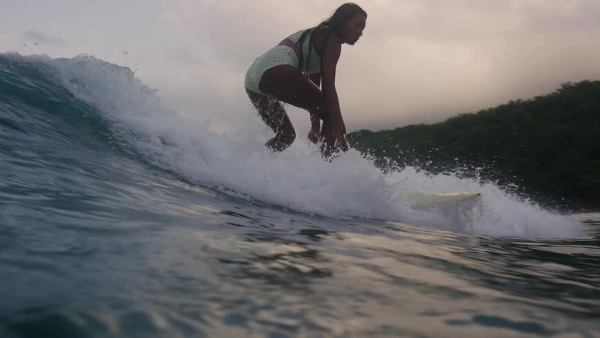 A woman rises on her surfboard and surfs an ocean wave