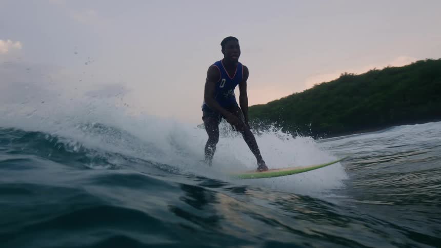 A male is surfing on a body of water during dusk