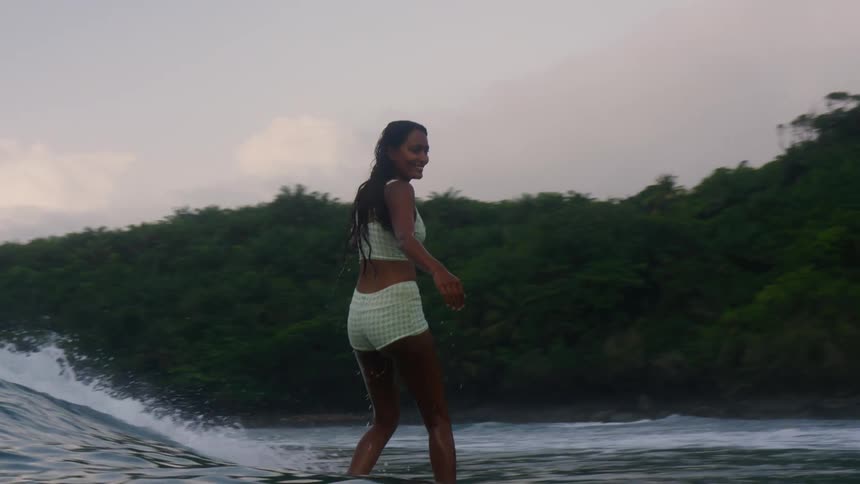 Woman surfing in the sea near some forest