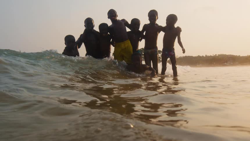 Group of boys jump in ocean as waves roll toward coast