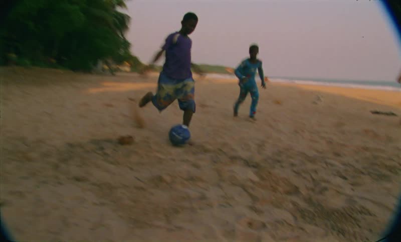 Children playing football on the beach next to ocean
