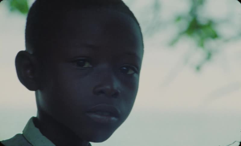 A young african boy looks inquisitively at something out of the shot