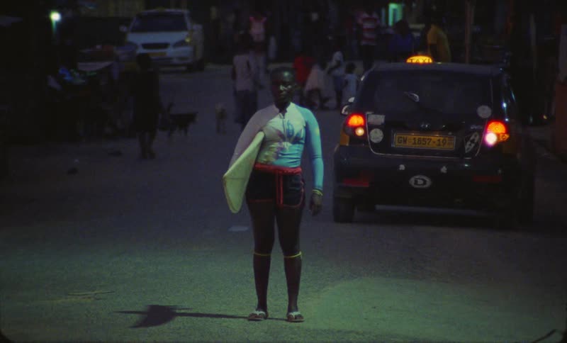 Woman holding surfboard stands on road in the city