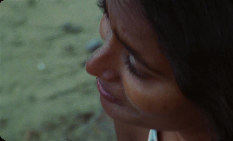 A young woman is sitting on the beach around the day time