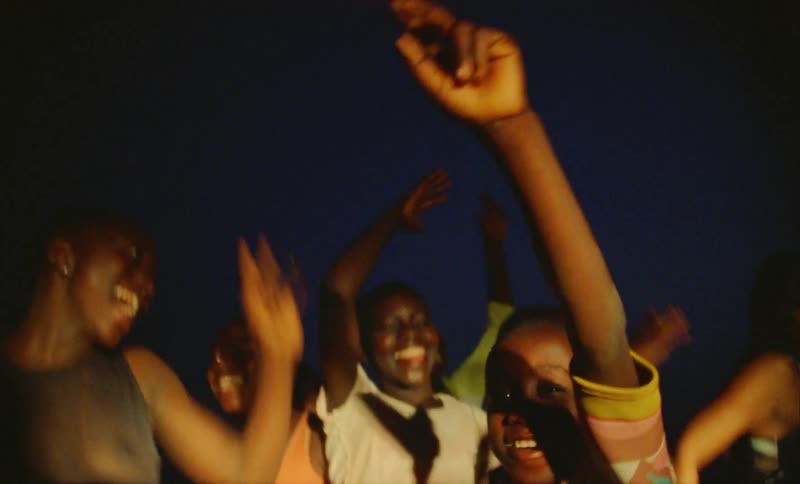 A group of young girls indoors in a dark room at a party dance and jump around
