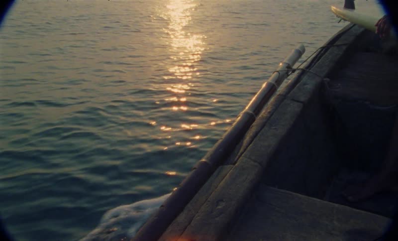 A boat is driving on a body of water at dusk