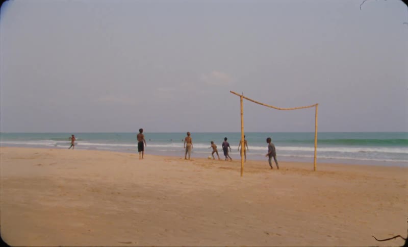 A group of boys play soccer on the beach