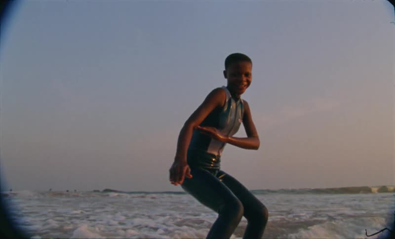 A boy rides into the shore on his surfboard