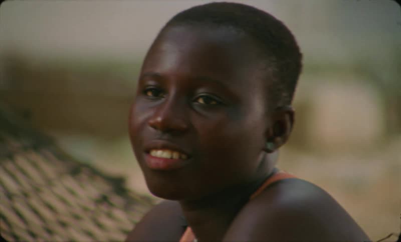 A woman looks into the distance while sitting on a hammock outdoors during the day
