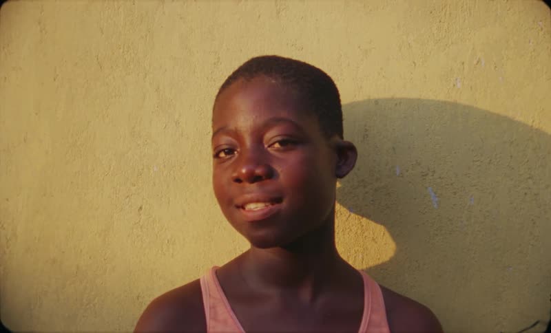 A boy is standing outdoors near a wall
