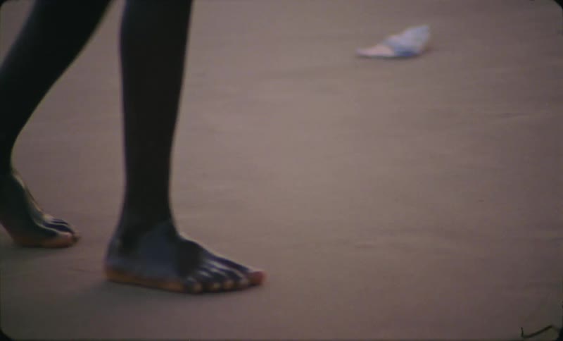 A child is walking on the beach coast with a surfboard