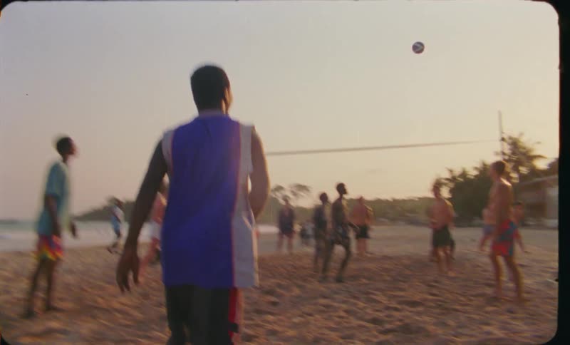 A large group of people are playing volleyball on the beach and the video is sped up