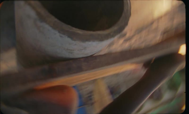 Chaotic close up of a concrete pipe with a person sitting on top at evening