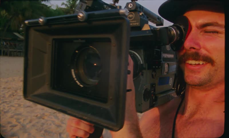 The view is of a man video taping people at the beach