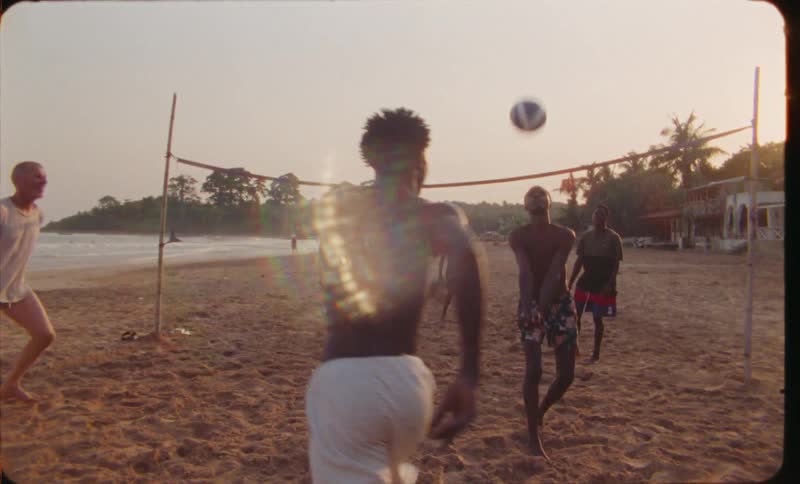 A group of men play volleyball on the beach