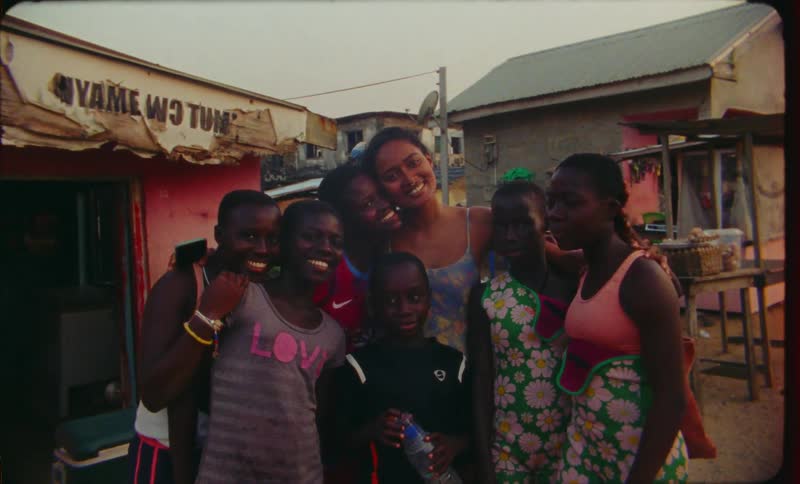 A group of children and teenagers pose for a picture in an urban thirdworld city
