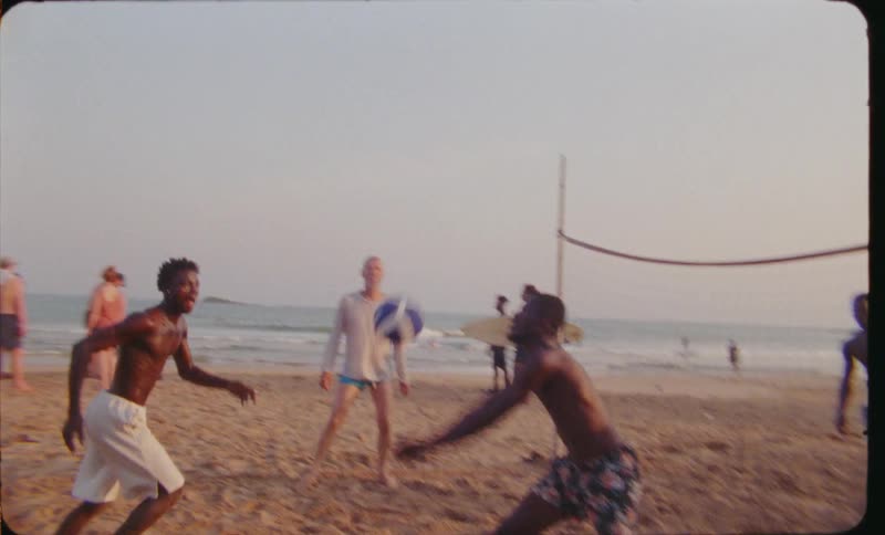 Teenage boys playing beach volleyball at the beach during the day