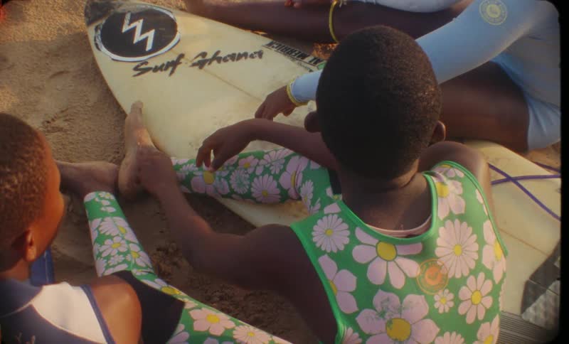 Children are sitting on a surfboard on the beach